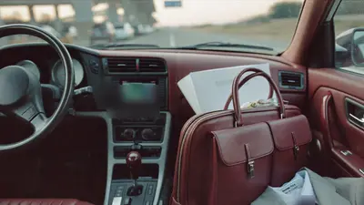 Borsa da lavoro in pelle sul sedile di un'auto all'alba in autostrada