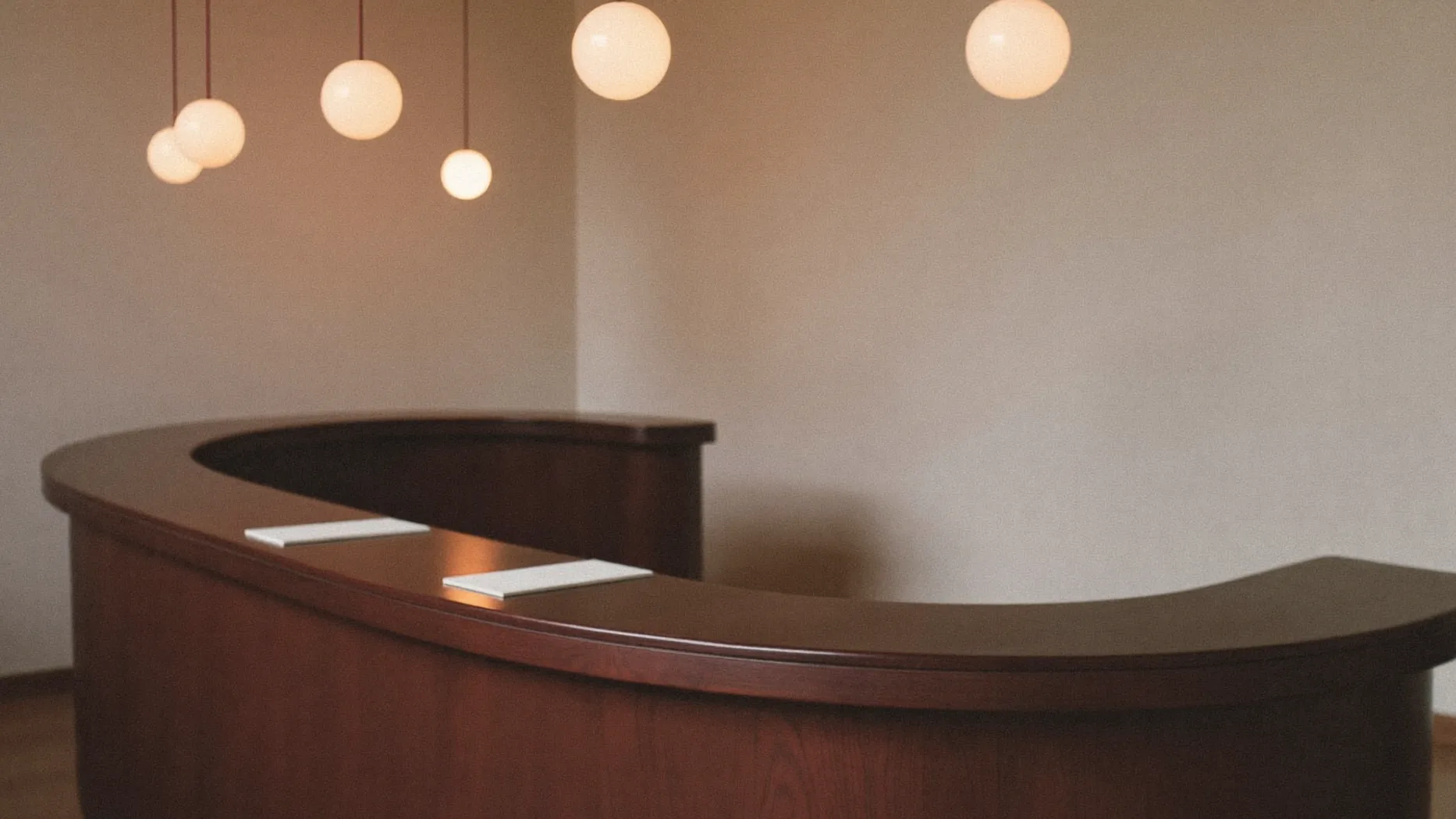 Reception moderna vuota con bancone curvo in legno e lampade a sospensione